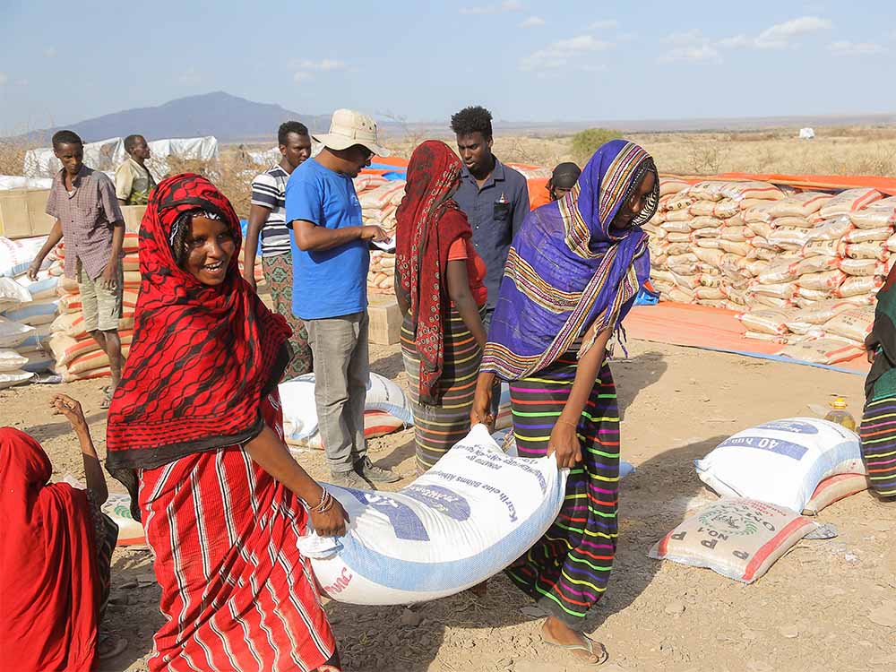 Zwei Frauen tragen einen Sack mit Lebensmittel in Äthiopien im Rahmen der Nothilfe von Menschen für Menschen